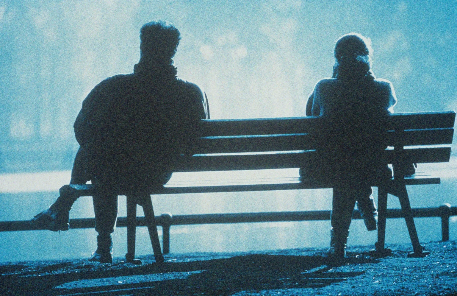 a man and a woman sitting on a bench in the park